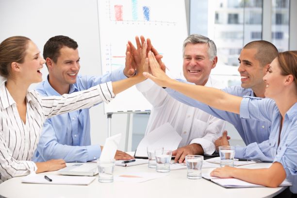 happy employees giving each other high fives at a meeting